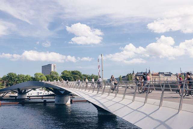 Cyclists traversing Lille Langebro Bridge on a sunny day