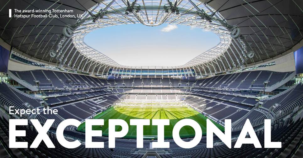 A stadium with a green field and a skylightDescription automatically generated